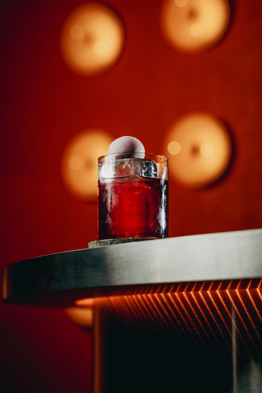Red drink on a steel table against the glowing orange wall
